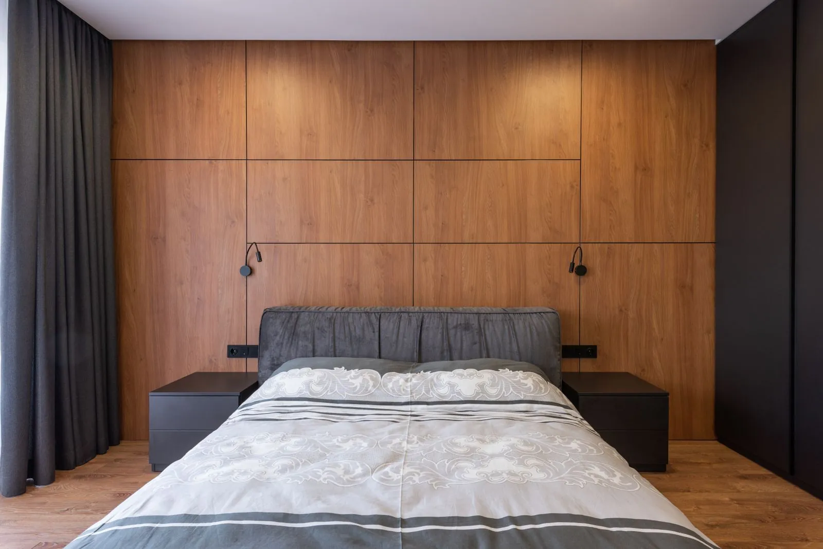Quarto com painel de madeira na cabeceira e mesas de cabeceira suspensas