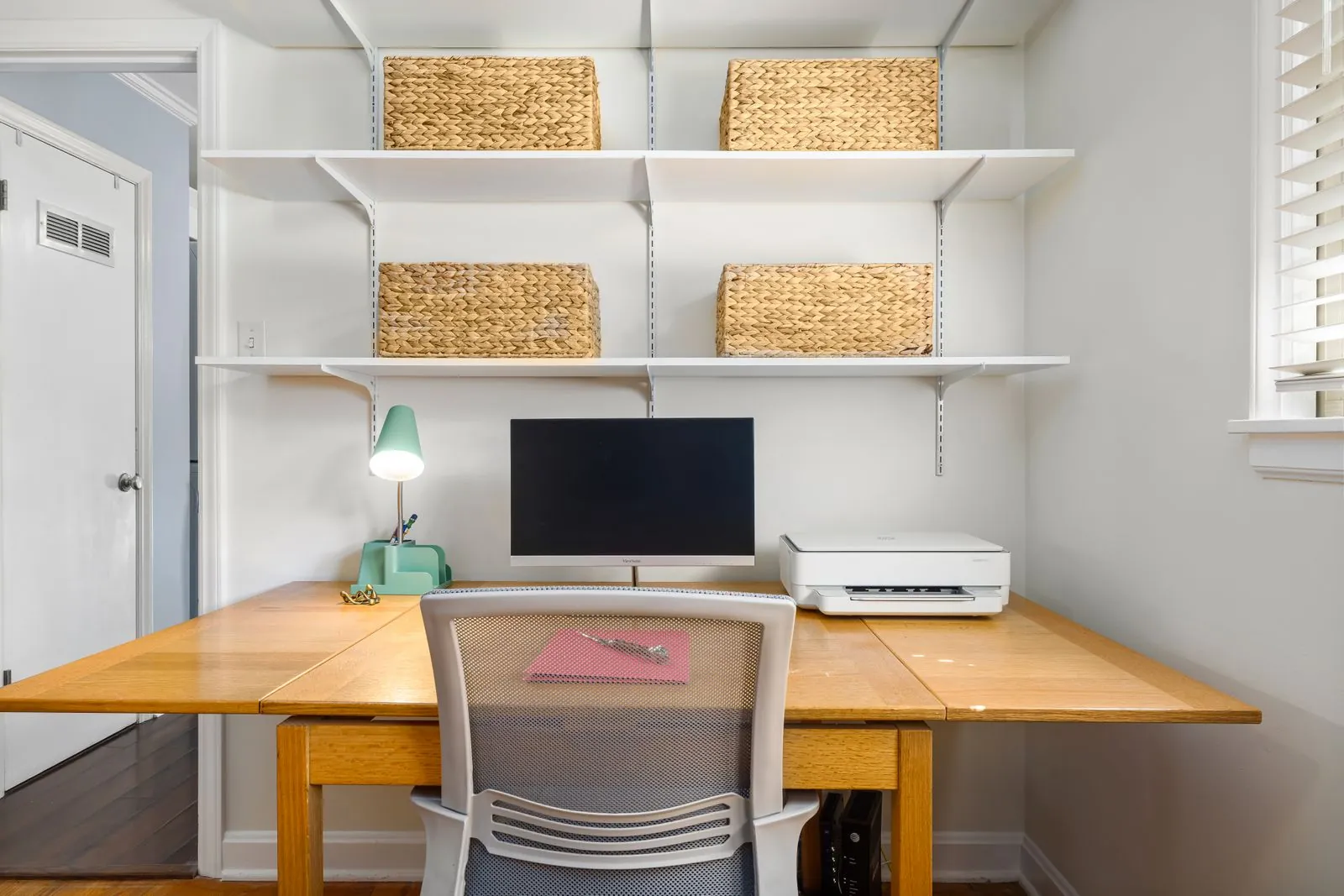 Home office com prateleiras na parede e bancada de trabalho em madeira